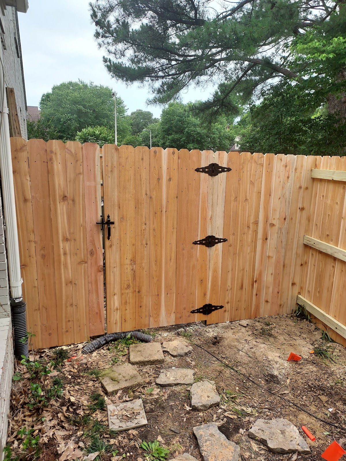 Backyard wood gate with black hardware beside a house
